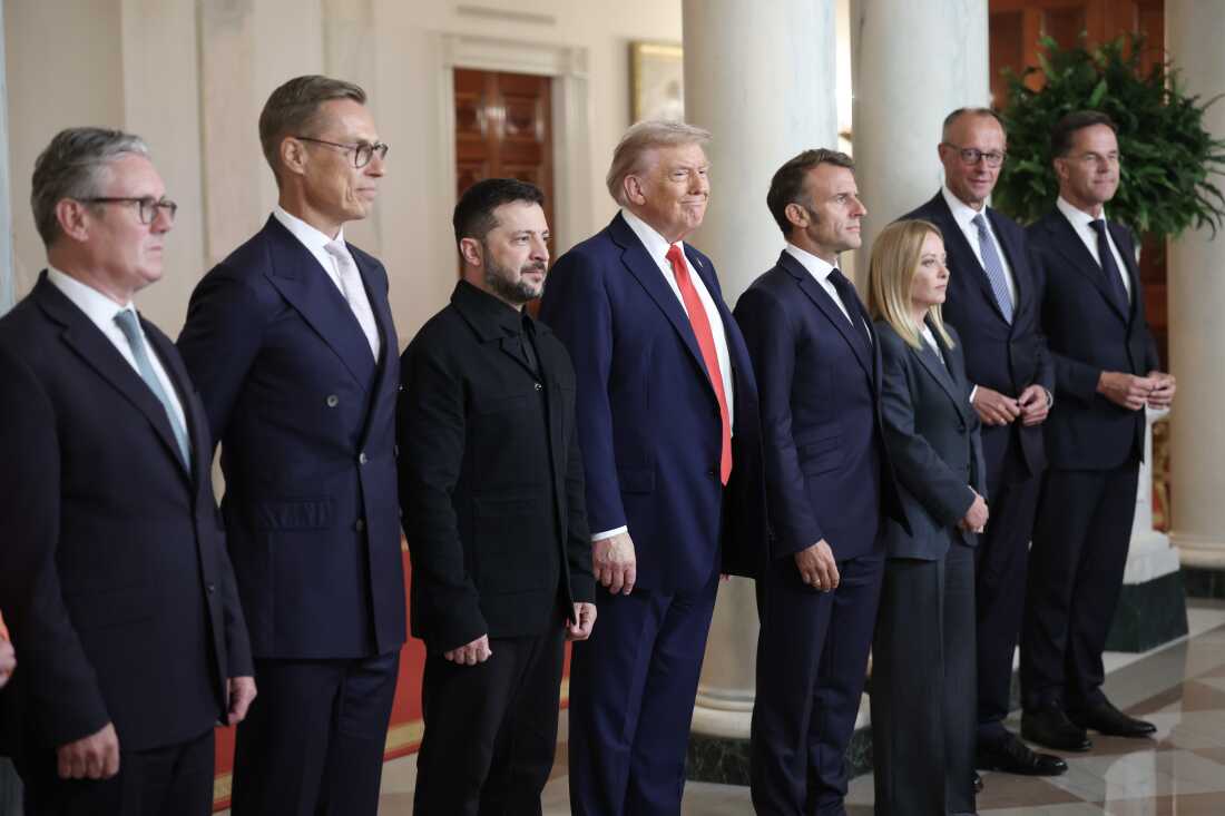 Un groupe de sept dirigeants et responsables mondiaux se tiennent debout en rang, à l'intérieur, vêtus de tenues de cérémonie, et regardent droit devant eux.